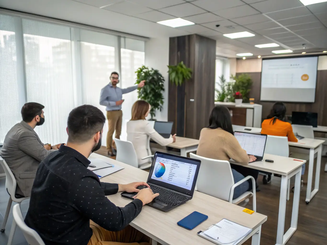 A trainer conducting a workshop with employees using laptops and presentation materials, showcasing Bessa Consultores' Corporate IT Training service.